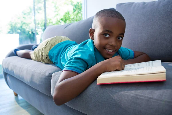 Junge liegt mit Roman auf Sofa — Stockfoto