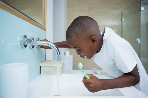 Boy spitting in sink and holding brush — Stock Photo, Image