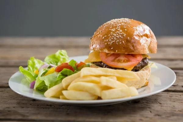 Hambúrguer e batatas fritas com legumes — Fotografia de Stock