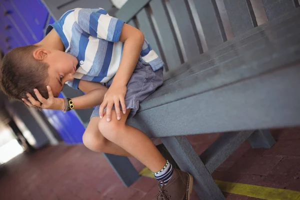 Smutny chłopiec z głową w ręku na ławce — Zdjęcie stockowe