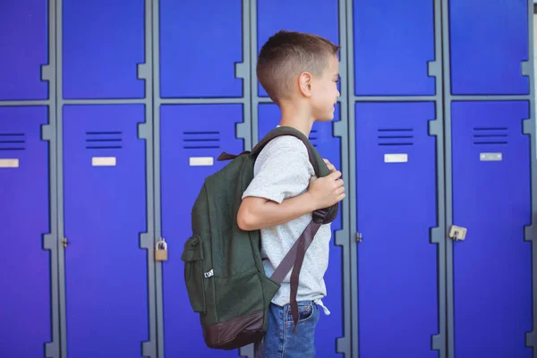 Niño llevando mochila contra casilleros — Foto de Stock