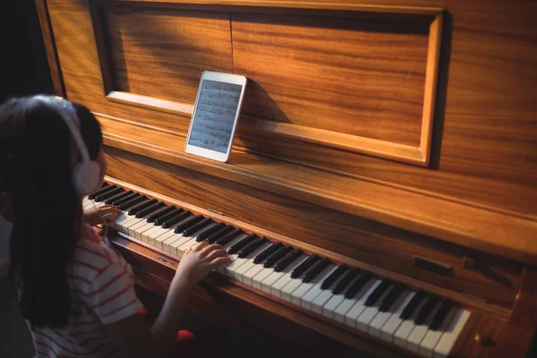 Flickan bär hörlurar samtidigt öva piano — Stockfoto