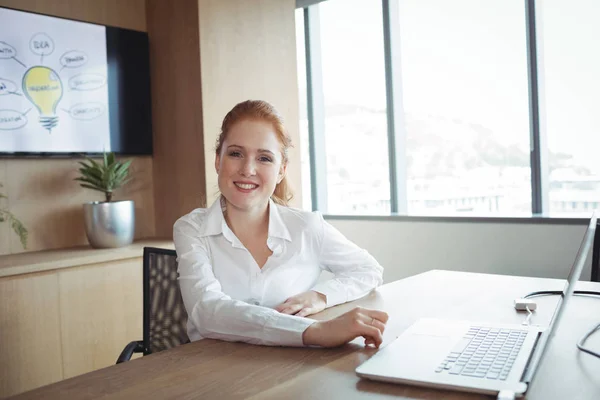 Femme d'affaires souriante assise au bureau — Photo