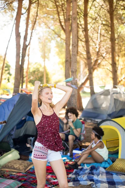 Woman standing with arms raised at campsite — Stock Photo, Image