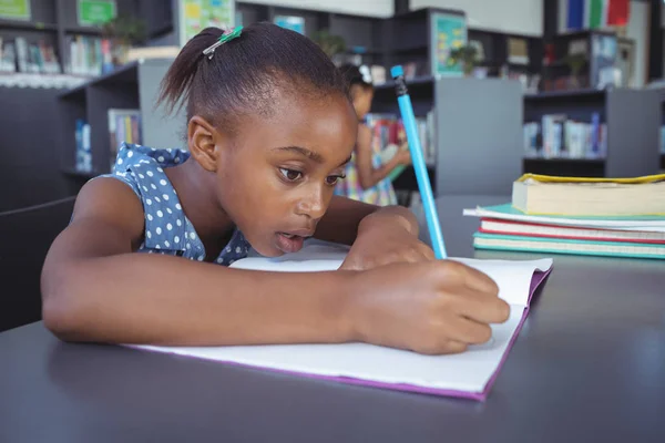 Menina estudando na mesa na biblioteca — Fotografia de Stock