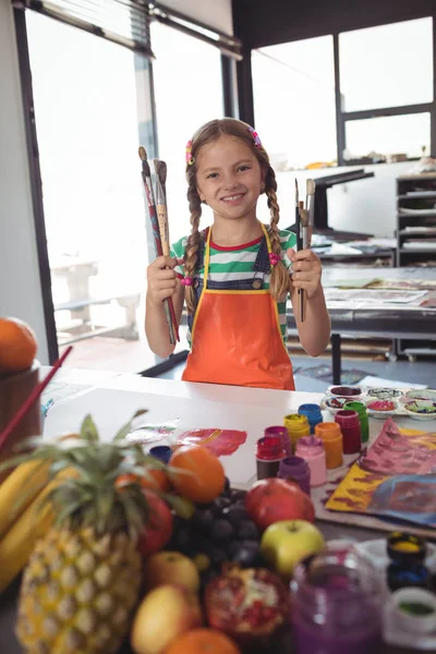 Ragazza che tiene pennelli da scrivania — Foto Stock