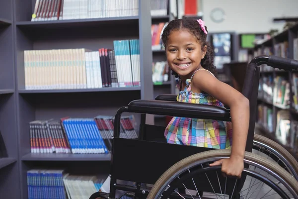 Menina sorridente em cadeira de rodas na biblioteca — Fotografia de Stock