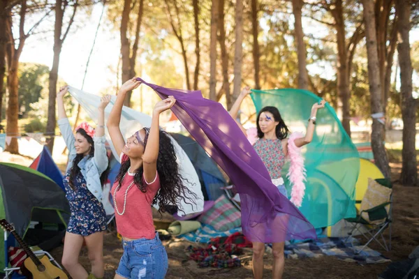 Female friends holding scarfs at campsite — Stock Photo, Image