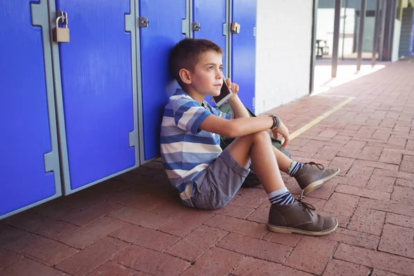 Boy mluví o telefonu při posezení u skříňky — Stock fotografie