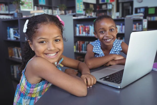 Девушки с ноутбуком за столом в библиотеке — стоковое фото
