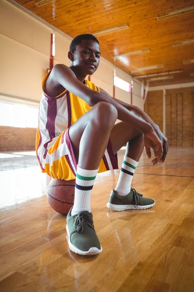 Jistý dospívající chlapec sedí na basketbal — Stock fotografie