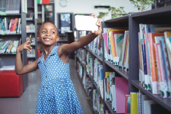 Mädchen macht Selfie vor Bücherregal in Bibliothek — Stockfoto