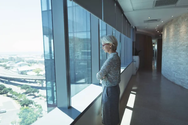 Задумчивая деловая женщина, стоящая у окна — стоковое фото