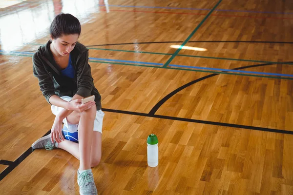 Frau benutzt Handy auf Basketballplatz — Stockfoto