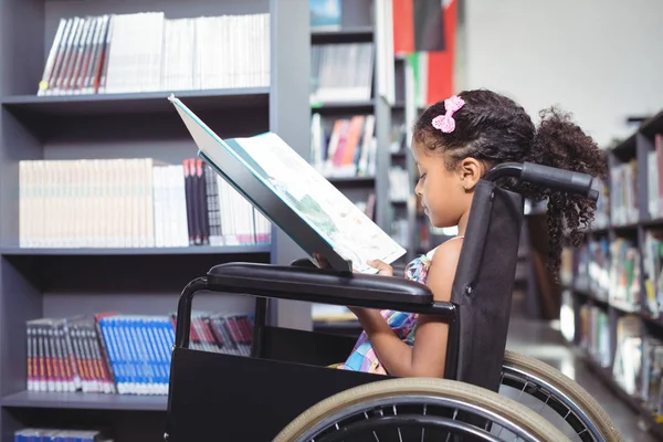 Girl reading book on wheelchair — Stock Photo, Image
