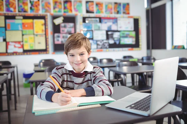 Elementary schoolboy studying in classroom — Stock Photo, Image