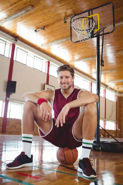 Jogador de basquete masculino sentado na bola — Fotografia de Stock