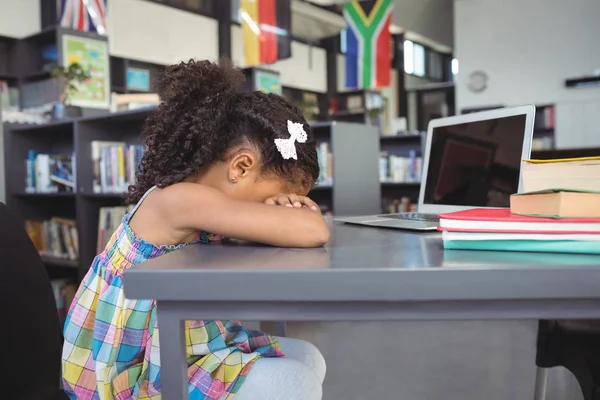Menina triste inclinando-se na mesa na biblioteca — Fotografia de Stock