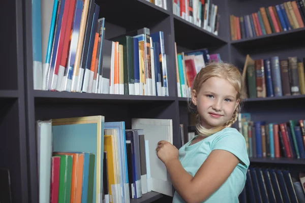 Meisje kiezen boek van de plank — Stockfoto