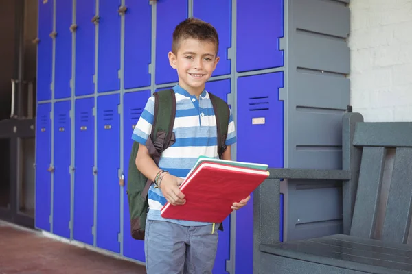 Smiling boy holding books in corridor — Stock Photo, Image