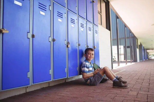 Niño sonriente sentado junto a taquillas — Foto de Stock