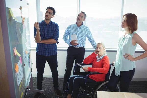 Business entrepreneurs looking at whiteboard — Stock Photo, Image