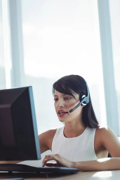 Geschäftsfrau spricht während der Arbeit über Headset — Stockfoto