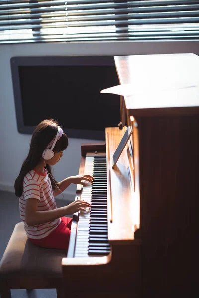 Flickan bär hörlurar samtidigt öva piano — Stockfoto