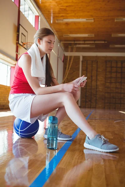 Женщина с помощью телефона на баскетбольной площадке — стоковое фото