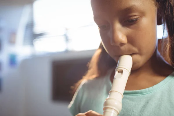 Nachdenkliches Mädchen spielt Flöte im Klassenzimmer — Stockfoto