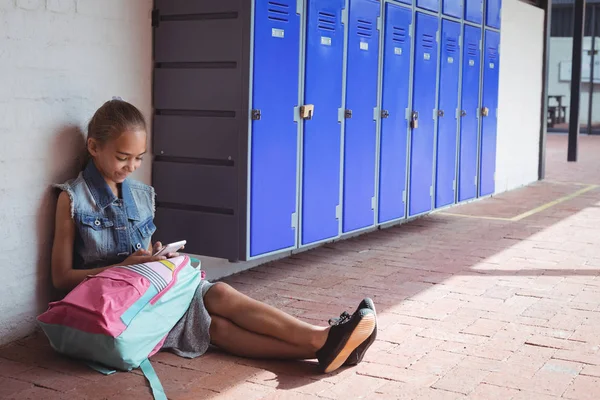 Ученик начальной школы с помощью мобильного телефона по шкафчикам — стоковое фото