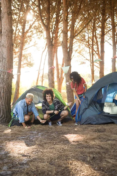 Uomo con gli amici allestimento tenda sul campo — Foto Stock