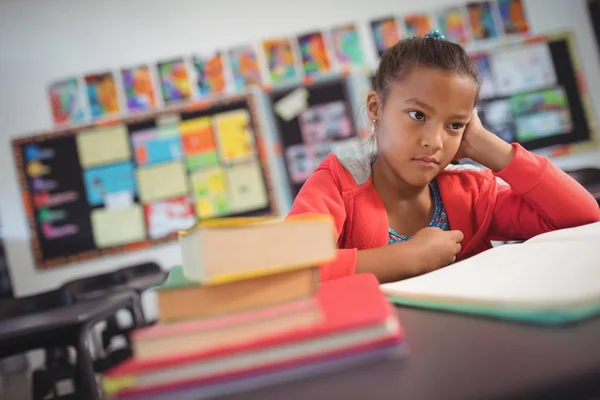 Doordachte schoolmeisje zit aan Bureau — Stockfoto