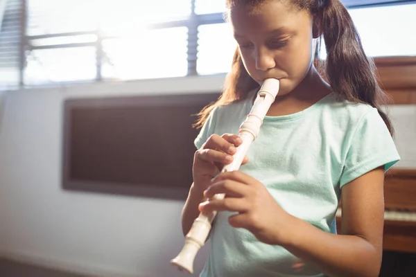 Fille pratiquant la flûte en classe — Photo