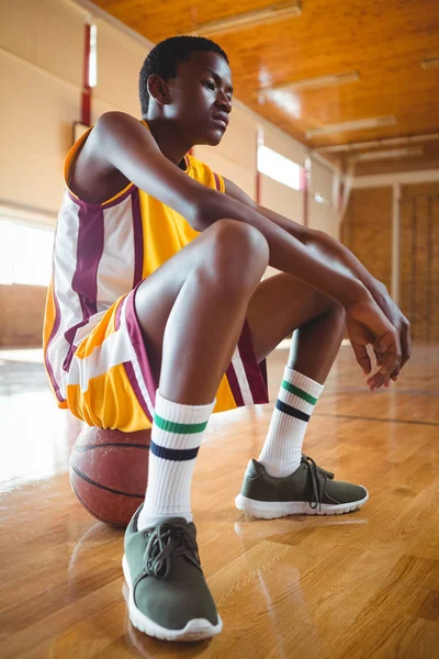 Promyšlené dospívající chlapec sedí na basketbal — Stock fotografie