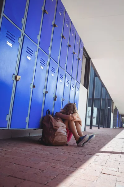 Schoolmeisje zit door kluisjes — Stockfoto