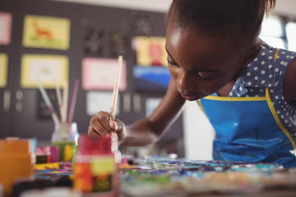 Concentrated elementary girl painting at desk — Stock Photo, Image