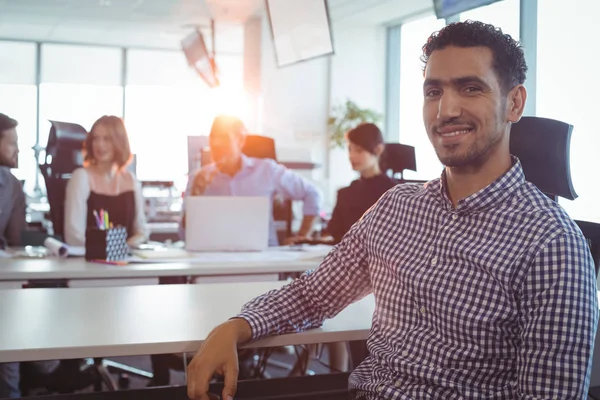 Businessman sitting at desk with colleagues — Stock Photo, Image