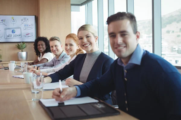 Χαμογελώντας επαγγελματίες άνθρωποι που κάθονται στο γραφείο — Φωτογραφία Αρχείου