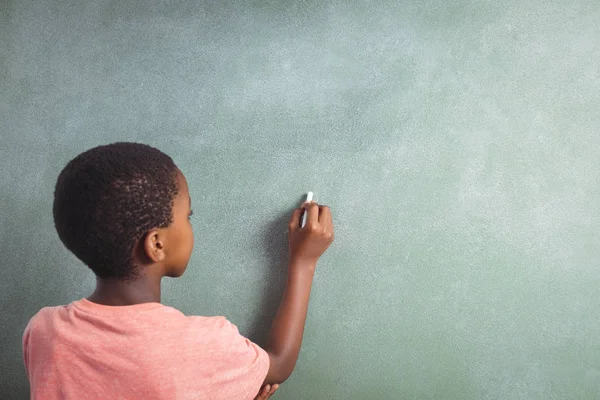 Chłopiec pisania kredą na greenboard w szkole — Zdjęcie stockowe