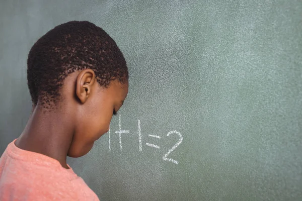 Boy standing by chalkboard — Stock Photo, Image