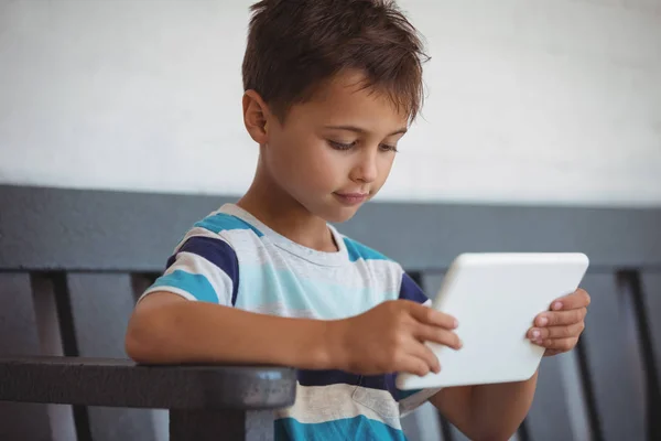 Junge benutzt Tablet während er auf Bank sitzt — Stockfoto