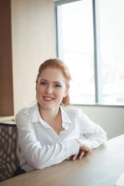 Sorrindo empresária sentada na mesa — Fotografia de Stock