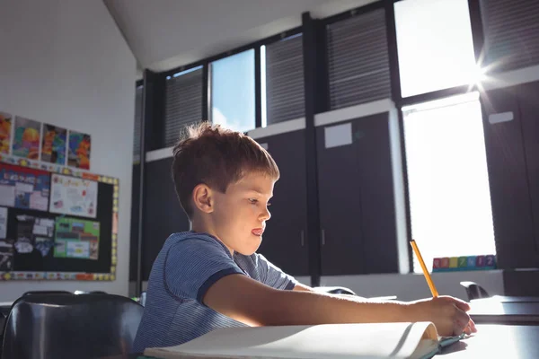 Jongen schrijven op boek op school — Stockfoto