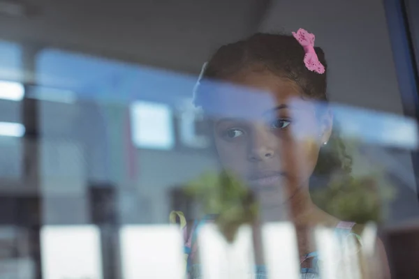 Споглянута дівчина дивиться через віконне скло — стокове фото