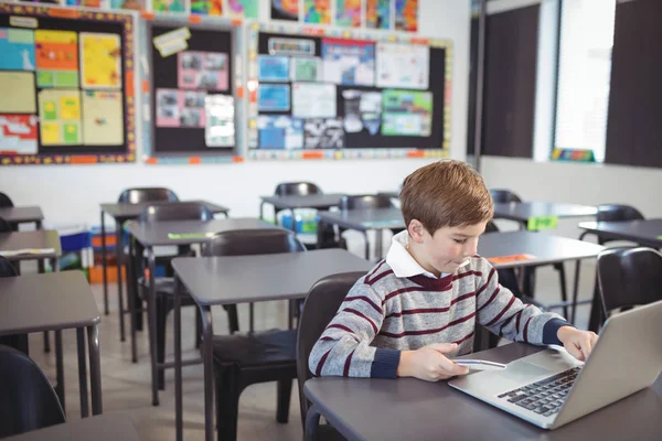 Uczeń za pomocą laptopa i telefon na biurko — Zdjęcie stockowe