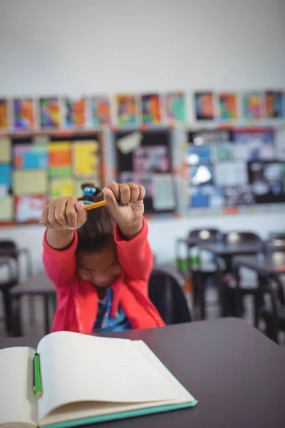 Fille étirant les mains tout en étant assis au bureau — Photo