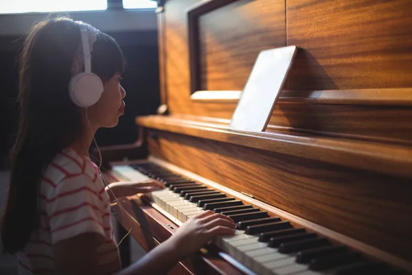 Flickan tittar på surfplatta samtidigt öva piano — Stockfoto