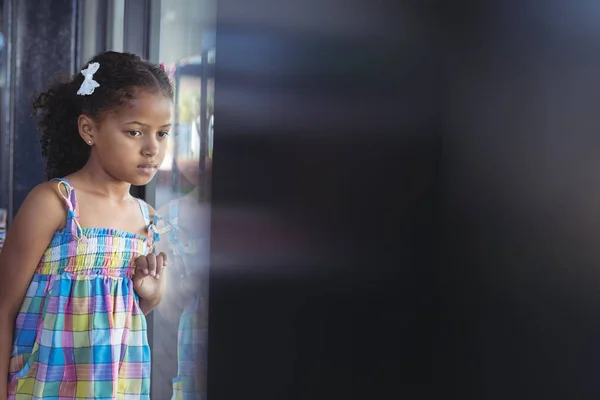 Ragazza premurosa guardando attraverso la finestra — Foto Stock