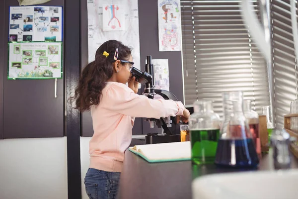 Elémentaire écolière en utilisant le microscope au laboratoire — Photo